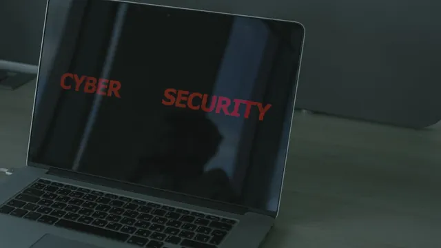 Laptop on a dark desk with the words cyber security glowing red across its screen